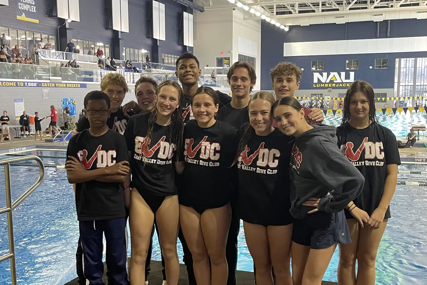 The team in club shirts poolside at an away meet.